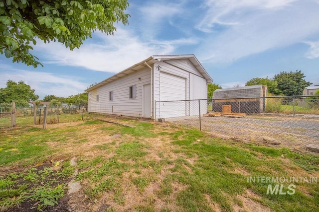 exterior space featuring a garage, a yard, and an outbuilding