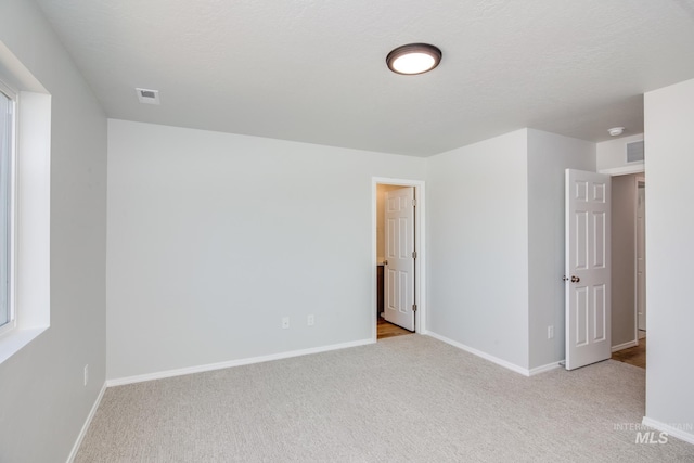 carpeted spare room with a textured ceiling