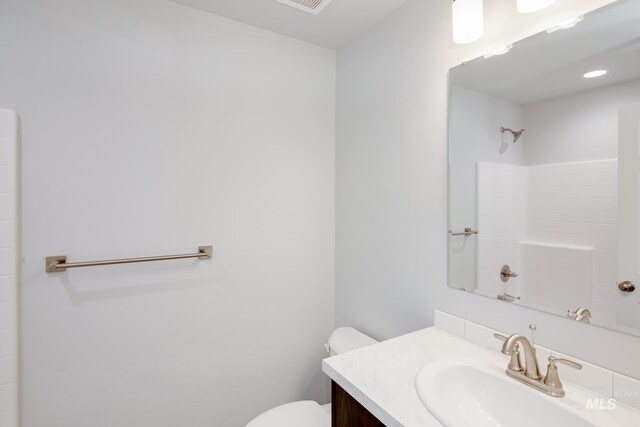 bathroom featuring walk in shower, vanity, and toilet