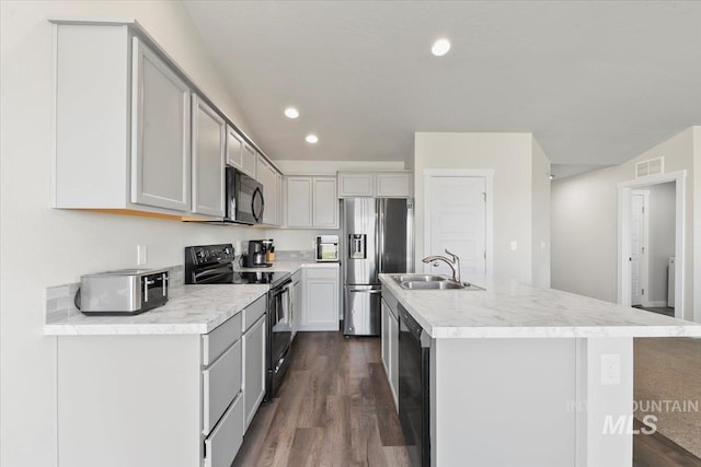 kitchen with dark hardwood / wood-style flooring, sink, an island with sink, and black appliances