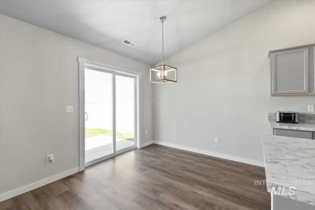 unfurnished dining area with a healthy amount of sunlight, dark hardwood / wood-style flooring, lofted ceiling, and an inviting chandelier