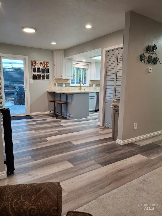 kitchen with white cabinetry, baseboards, light countertops, recessed lighting, and light wood-style flooring