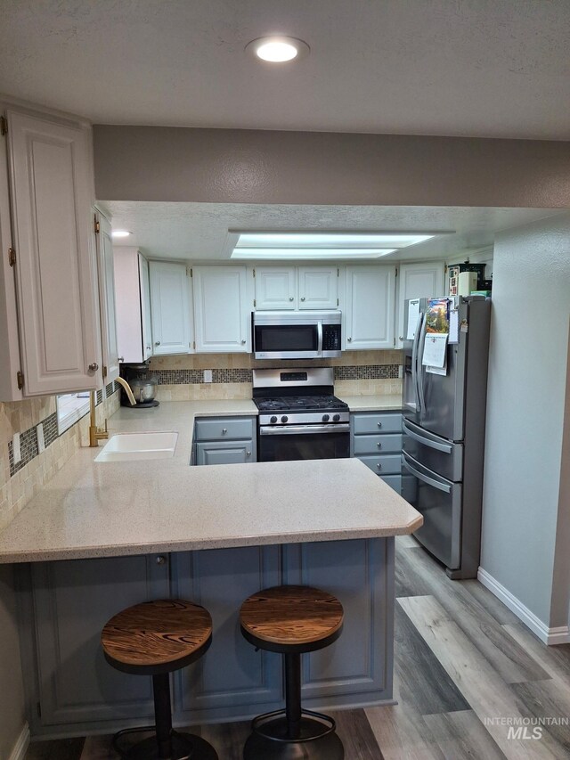 kitchen featuring appliances with stainless steel finishes, a sink, a peninsula, and light countertops