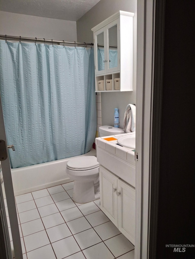 full bathroom with tile patterned flooring, shower / bath combo, toilet, vanity, and a textured ceiling