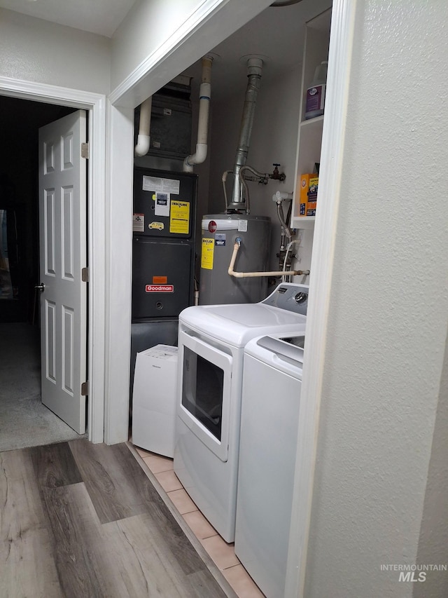 clothes washing area featuring separate washer and dryer, water heater, and light wood-type flooring