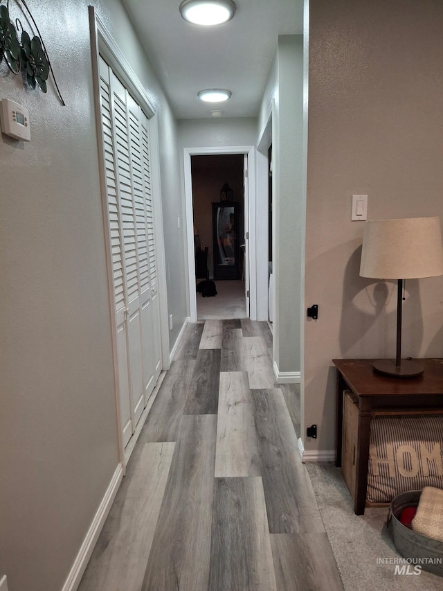 hallway featuring wood finished floors and baseboards