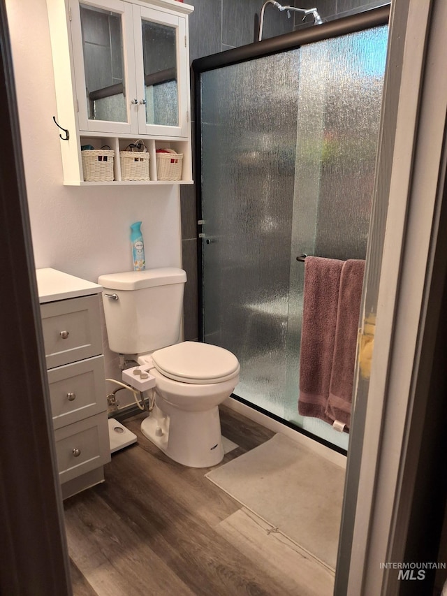 full bath featuring wood finished floors, toilet, a stall shower, and vanity
