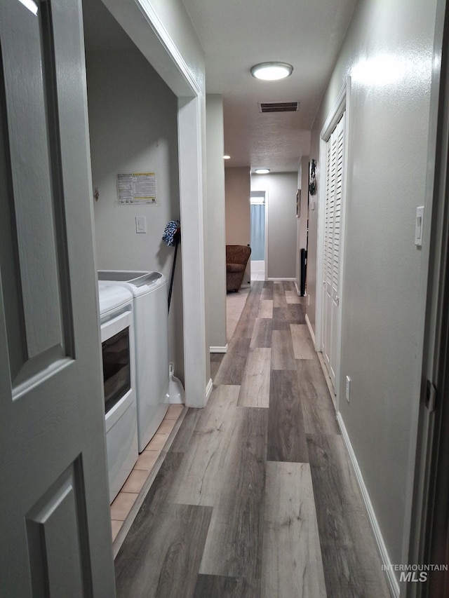 hallway featuring washer and dryer, wood finished floors, and baseboards