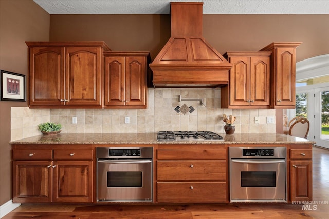 8585 W Rioja St, Star, ID 83669 - kitchen with oven, premium range hood, gas cooktop, light stone countertops, and a textured ceiling