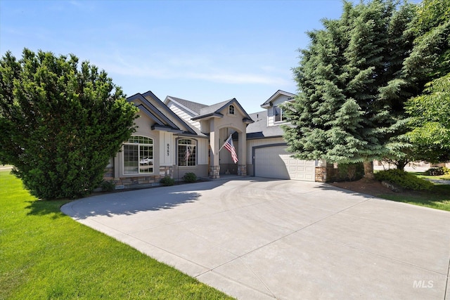 8585 W Rioja St, Star, ID 83669 - view of front of house with stone siding, an attached garage, driveway, a front lawn, and stucco siding