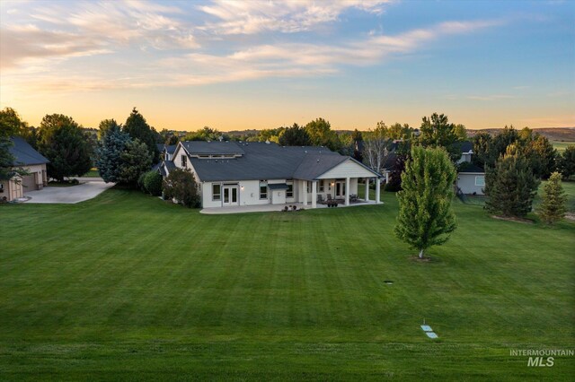 8585 W Rioja St, Star, ID 83669 - back of house at dusk featuring a lawn and a patio