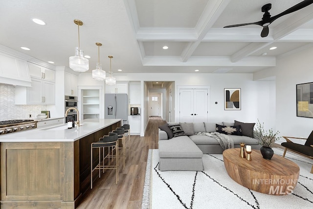 living room with beam ceiling, recessed lighting, light wood-style floors, and coffered ceiling