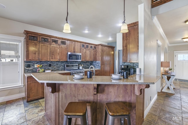 kitchen with decorative backsplash, a kitchen breakfast bar, hanging light fixtures, and appliances with stainless steel finishes