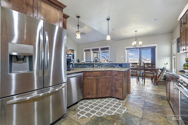 kitchen featuring a chandelier, stainless steel appliances, light stone counters, sink, and decorative light fixtures