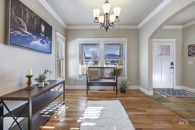 entrance foyer with an inviting chandelier, crown molding, and hardwood / wood-style flooring