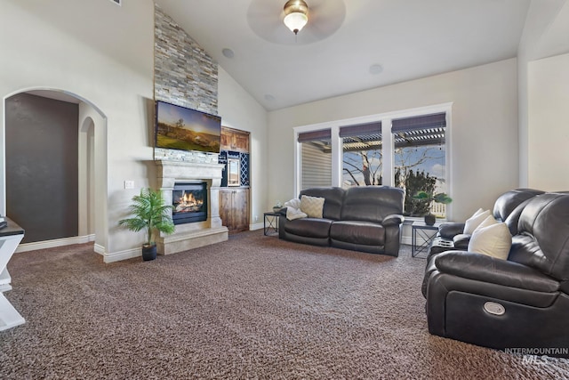 carpeted living room with high vaulted ceiling, a large fireplace, and ceiling fan