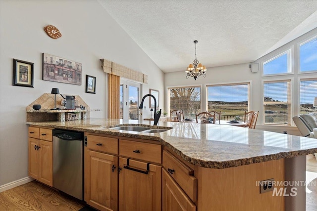 kitchen with light wood finished floors, dishwasher, lofted ceiling, light stone counters, and a sink