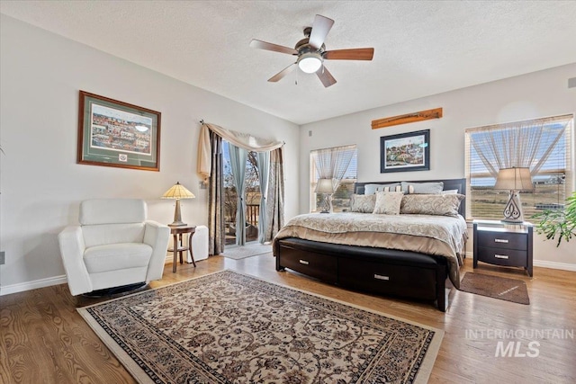 bedroom featuring access to exterior, wood finished floors, and a textured ceiling