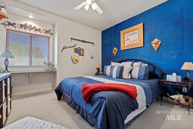 carpeted bedroom with baseboards, ceiling fan, and an accent wall