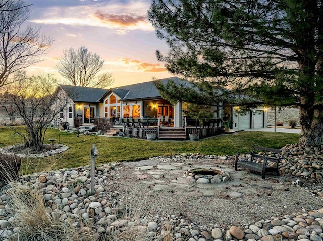 back of house at dusk featuring a fire pit and a yard