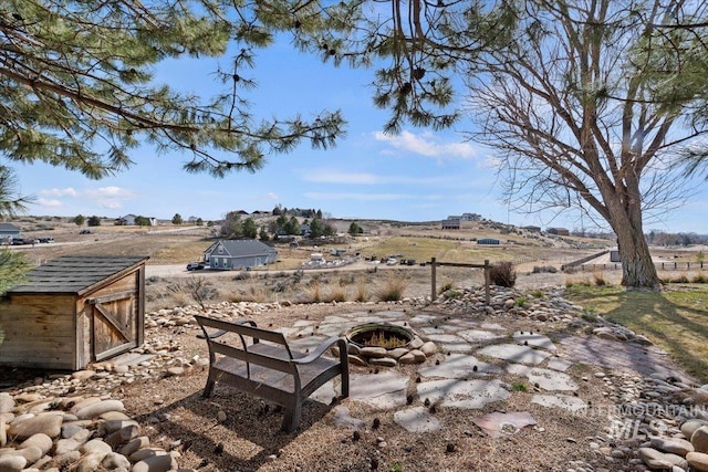 view of yard featuring a shed, a rural view, an outdoor fire pit, and an outdoor structure