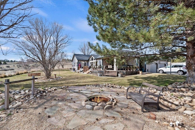 view of yard with a wooden deck, a fire pit, and a garage