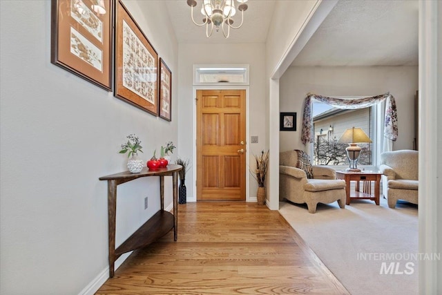 entryway featuring light wood-type flooring, baseboards, and an inviting chandelier