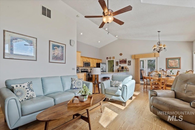 living area with light wood-type flooring, visible vents, high vaulted ceiling, ceiling fan with notable chandelier, and a textured ceiling