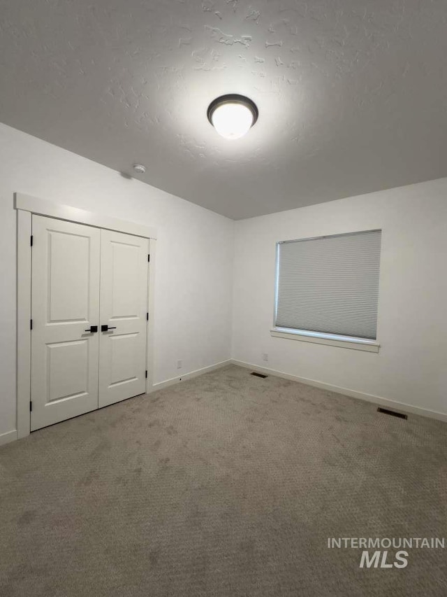 carpeted empty room with visible vents, baseboards, and a textured ceiling