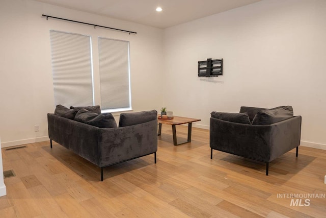 living room with recessed lighting, visible vents, baseboards, and light wood-style flooring