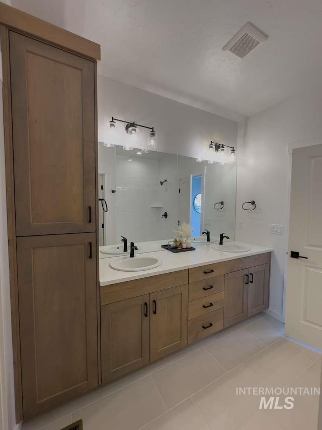 full bath with tile patterned floors, double vanity, visible vents, and a sink