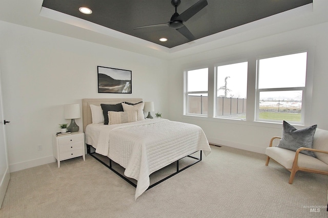 carpeted bedroom featuring ceiling fan and a tray ceiling