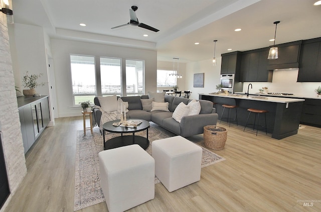 living room featuring ceiling fan, sink, and light hardwood / wood-style floors