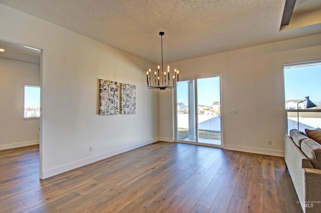 5728 S Keyport Way, Meridian, ID 83642 - unfurnished dining area with a chandelier, baseboards, wood finished floors, and a textured ceiling