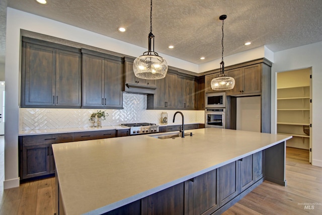 5728 S Keyport Way, Meridian, ID 83642 - kitchen featuring appliances with stainless steel finishes, a sink, decorative backsplash, a textured ceiling, and a spacious island