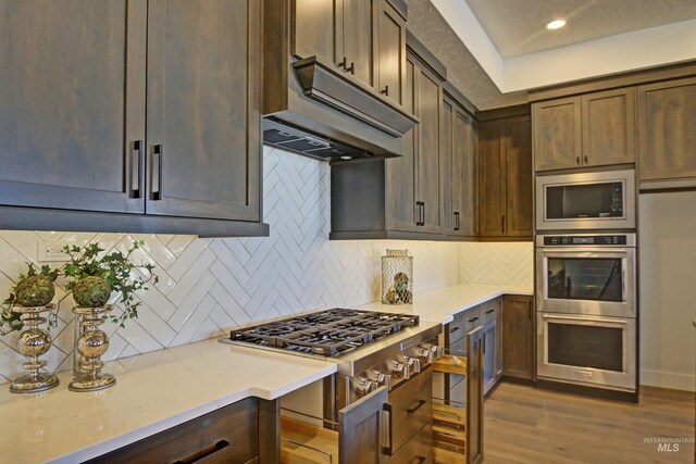 5728 S Keyport Way, Meridian, ID 83642 - kitchen featuring under cabinet range hood, stainless steel appliances, light countertops, wood finished floors, and backsplash