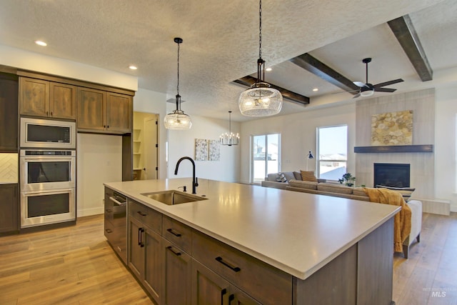 5728 S Keyport Way, Meridian, ID 83642 - kitchen featuring a sink, light wood-style flooring, a fireplace, ceiling fan, and beam ceiling