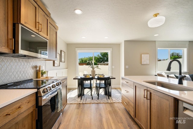 1132 S Barberry Pl, Nampa, ID 83686 - kitchen featuring stainless steel appliances, a sink, light wood-style flooring, brown cabinetry, and light countertops