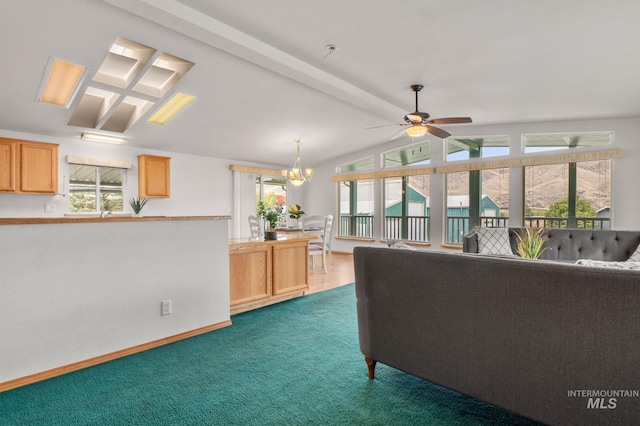 carpeted living room featuring vaulted ceiling with beams and ceiling fan with notable chandelier