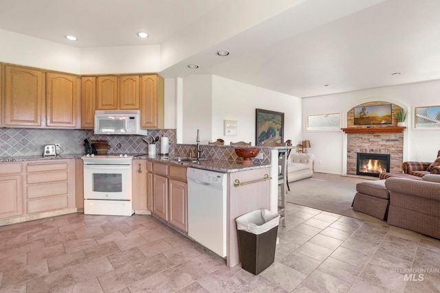 kitchen featuring sink, white appliances, backsplash, kitchen peninsula, and dark stone counters