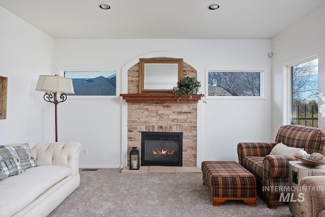 living room featuring light colored carpet and a stone fireplace