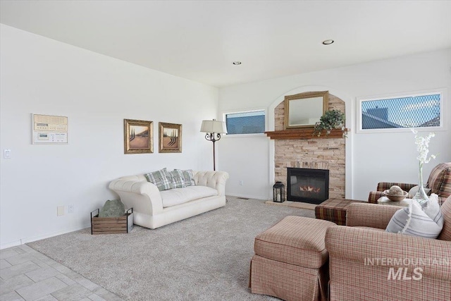 carpeted living room with a stone fireplace