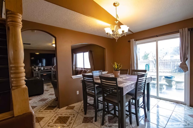 dining room with lofted ceiling, a healthy amount of sunlight, a notable chandelier, and a textured ceiling