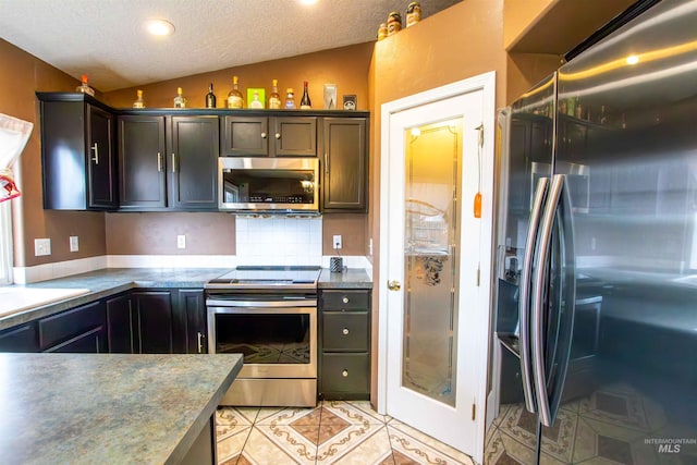 kitchen with lofted ceiling, a textured ceiling, dark brown cabinets, light tile patterned floors, and stainless steel appliances