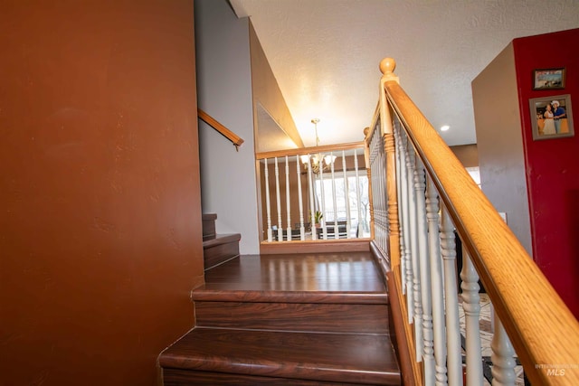 stairway featuring hardwood / wood-style flooring, a textured ceiling, and a chandelier