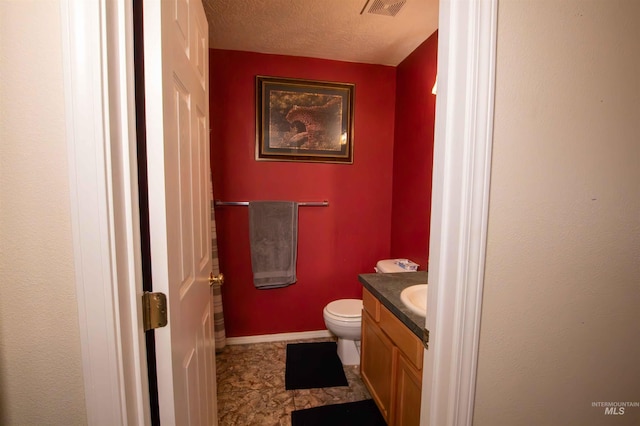 bathroom featuring vanity, toilet, and a textured ceiling