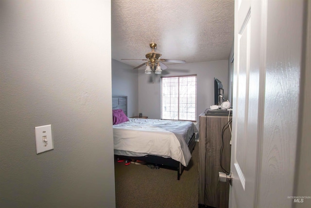 bedroom with ceiling fan, carpet floors, and a textured ceiling