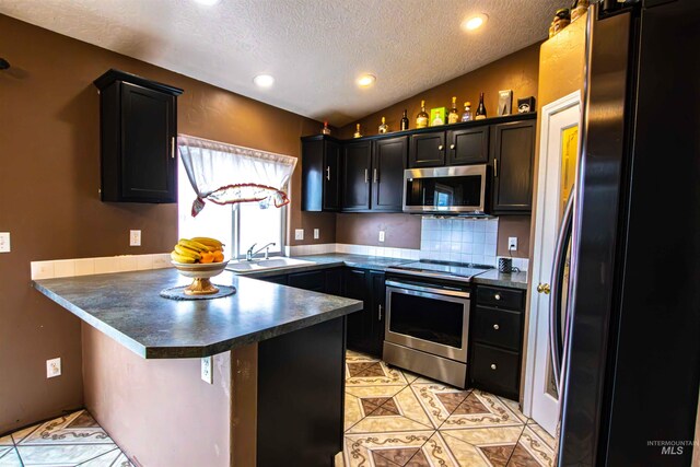 kitchen featuring lofted ceiling, a kitchen bar, sink, kitchen peninsula, and stainless steel appliances