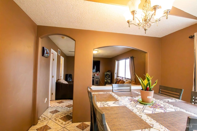 dining area featuring a textured ceiling and a chandelier