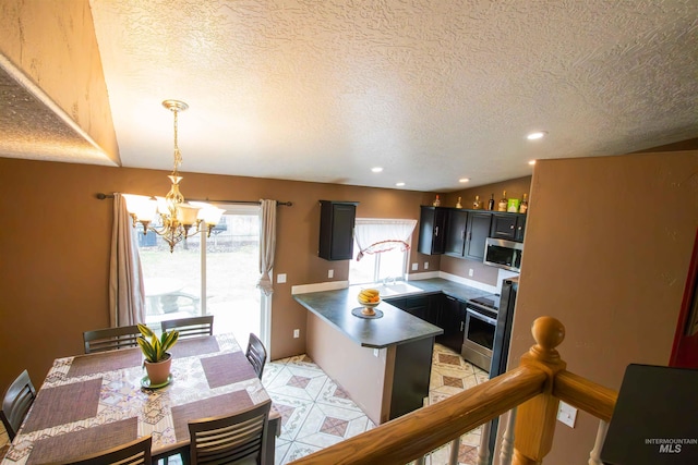 kitchen featuring a chandelier, hanging light fixtures, kitchen peninsula, stainless steel appliances, and a textured ceiling